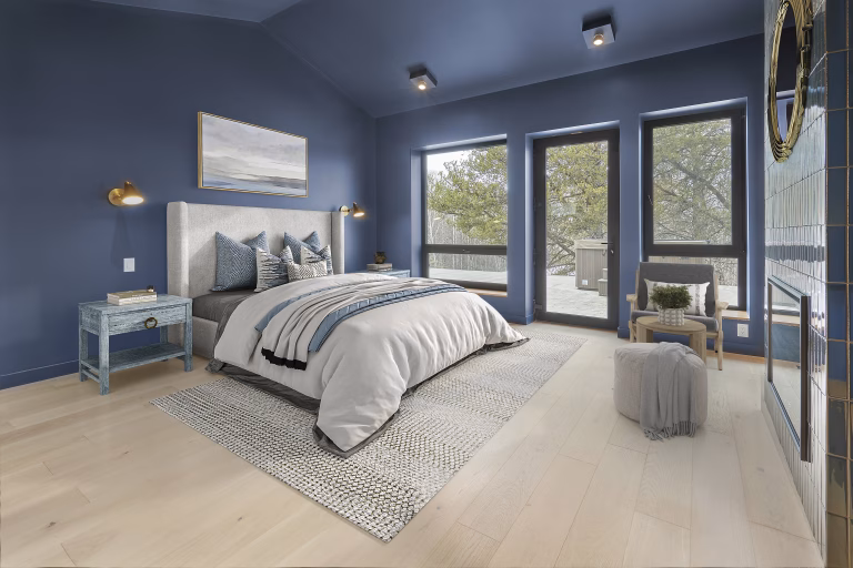 Blue-colored bedroom with widescreen windows, and a soft white bed on top of a light-gray carpet