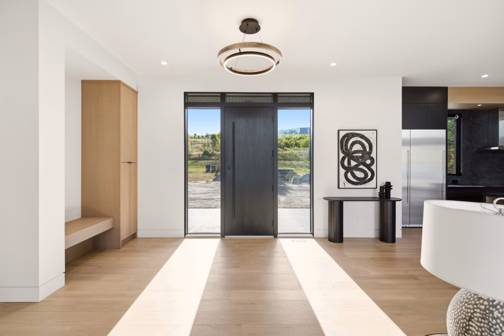 Entry foyer of an Osoyoos custom home looking out through glass sidelights to vineyard rows on the slope beyond.