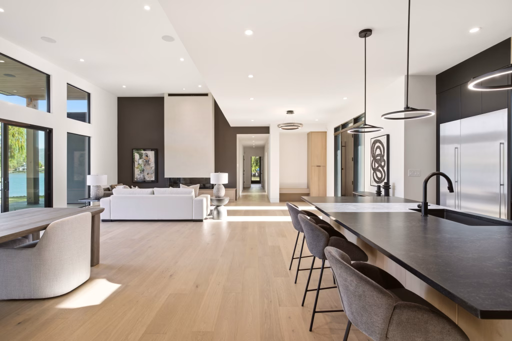 Stone-topped kitchen island and dining area open to the great room and lake views in this Osoyoos custom home.
