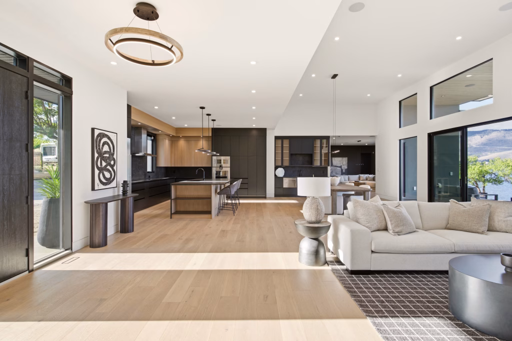 Open kitchen and living area with lake and mountain views through sliding glass doors in this Osoyoos custom home.