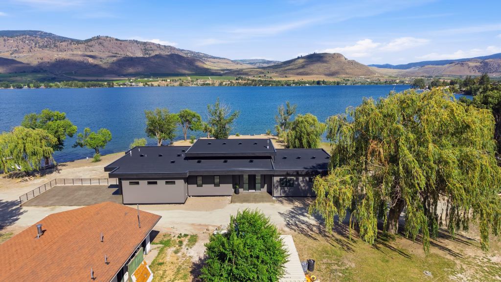 Aerial view of this single-storey Osoyoos lakefront home with the lake and dry Okanagan hills stretching behind it.