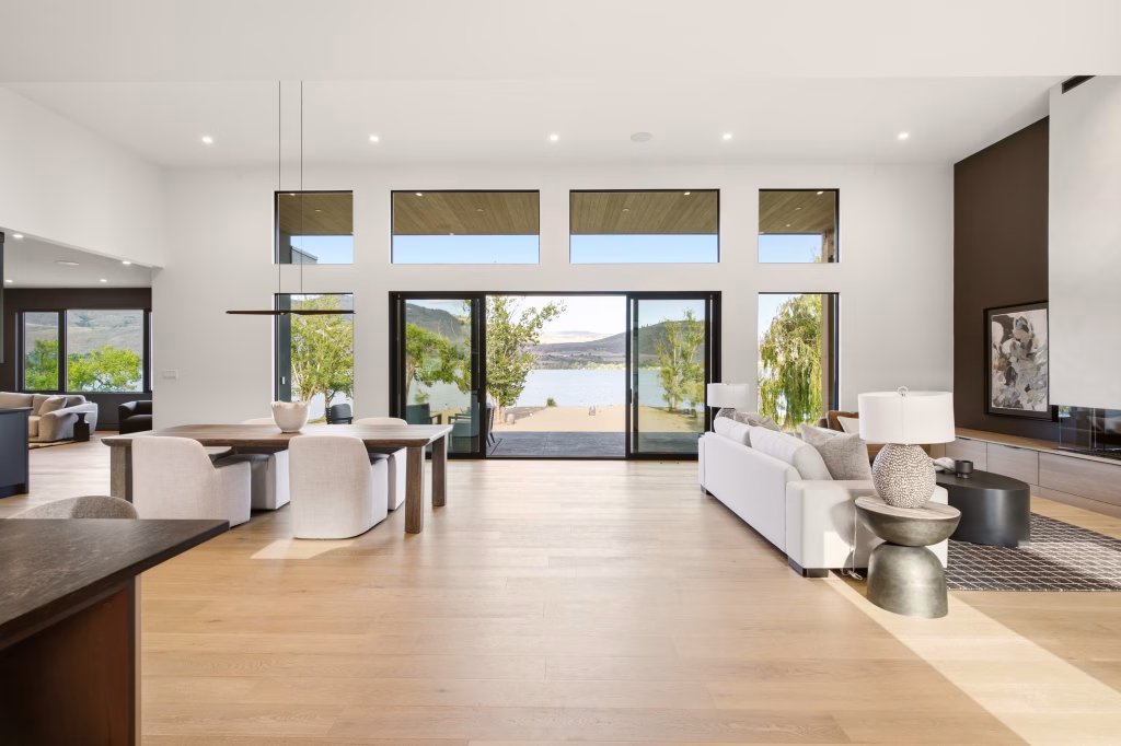 Dining and living area opening to a lakeside patio through sliding glass doors in this Osoyoos lakefront home.